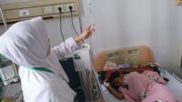 Tenaga kesehatan melakukan pengecekan Infus seorang pasien Demam Berdarah Dengue
