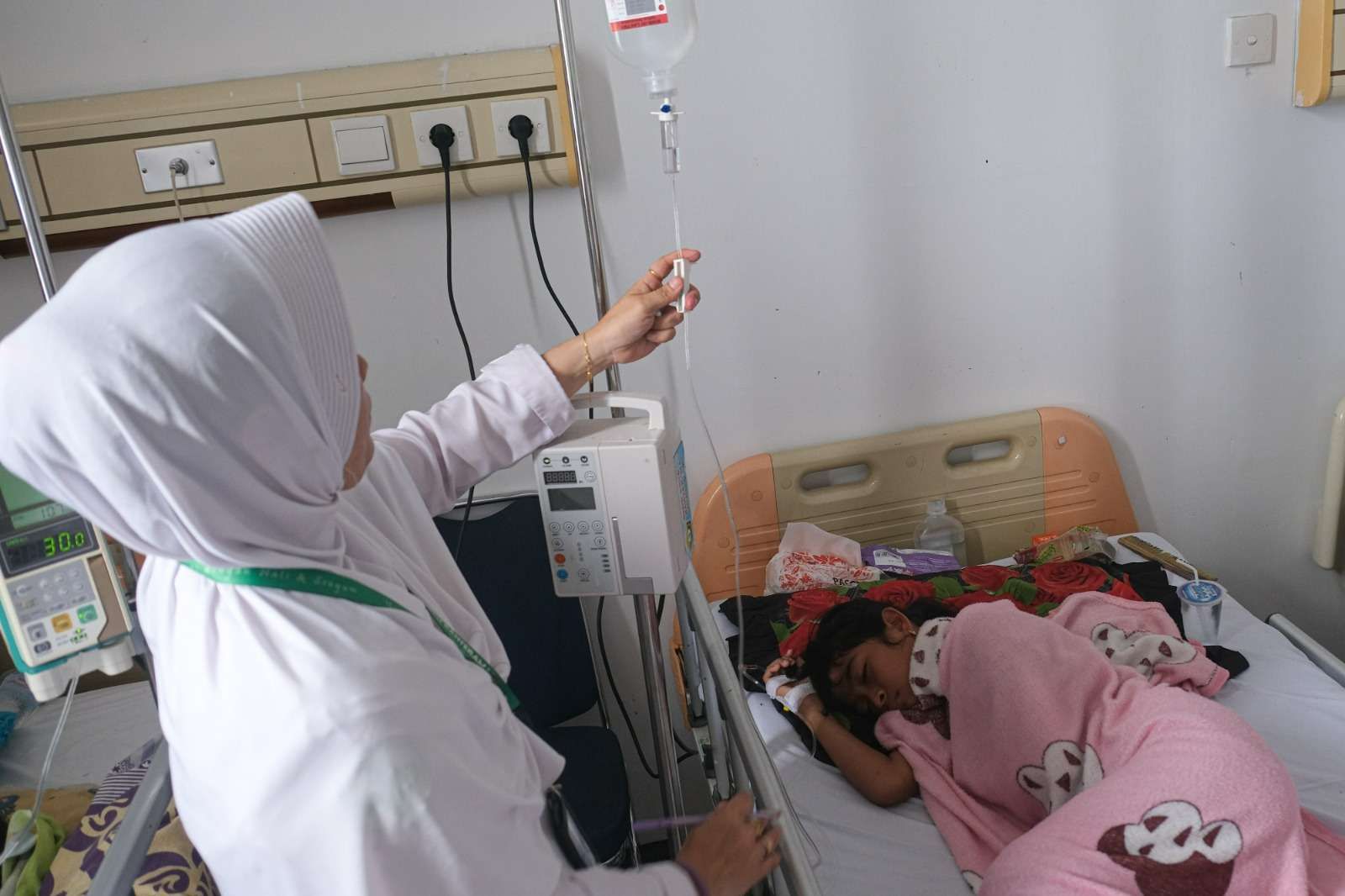 Tenaga kesehatan melakukan pengecekan Infus seorang pasien Demam Berdarah Dengue